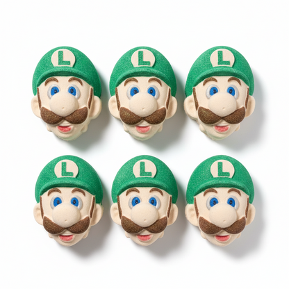 Four Luigi-themed bath bombs with green hats and facial features on a textured surface.