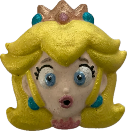 Toy figure of princess peach with yellow hair and a crown on a white background